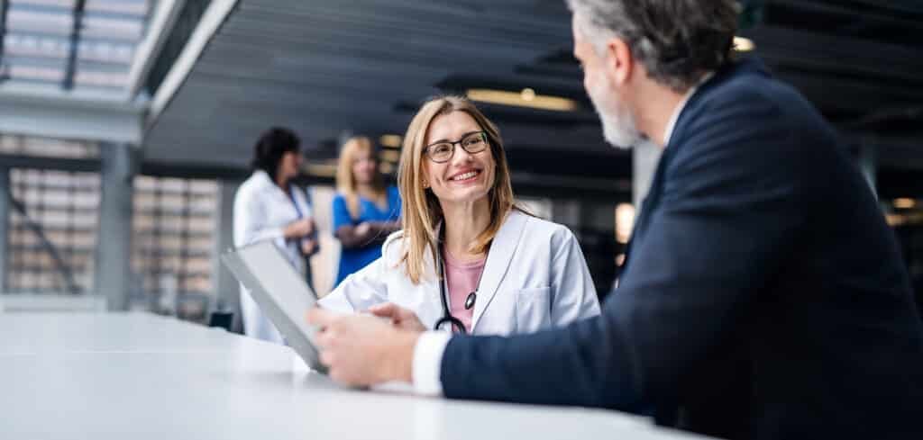 Female doctor talking to pharmaceutical sales representative on conference.